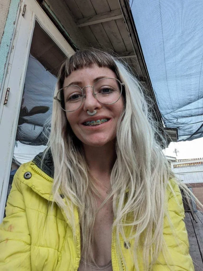 xGhoull (@ghouleeghoul) Blonde girl with braces OnlyFans model sexy picture wearing yellow jacket with nose piercing.